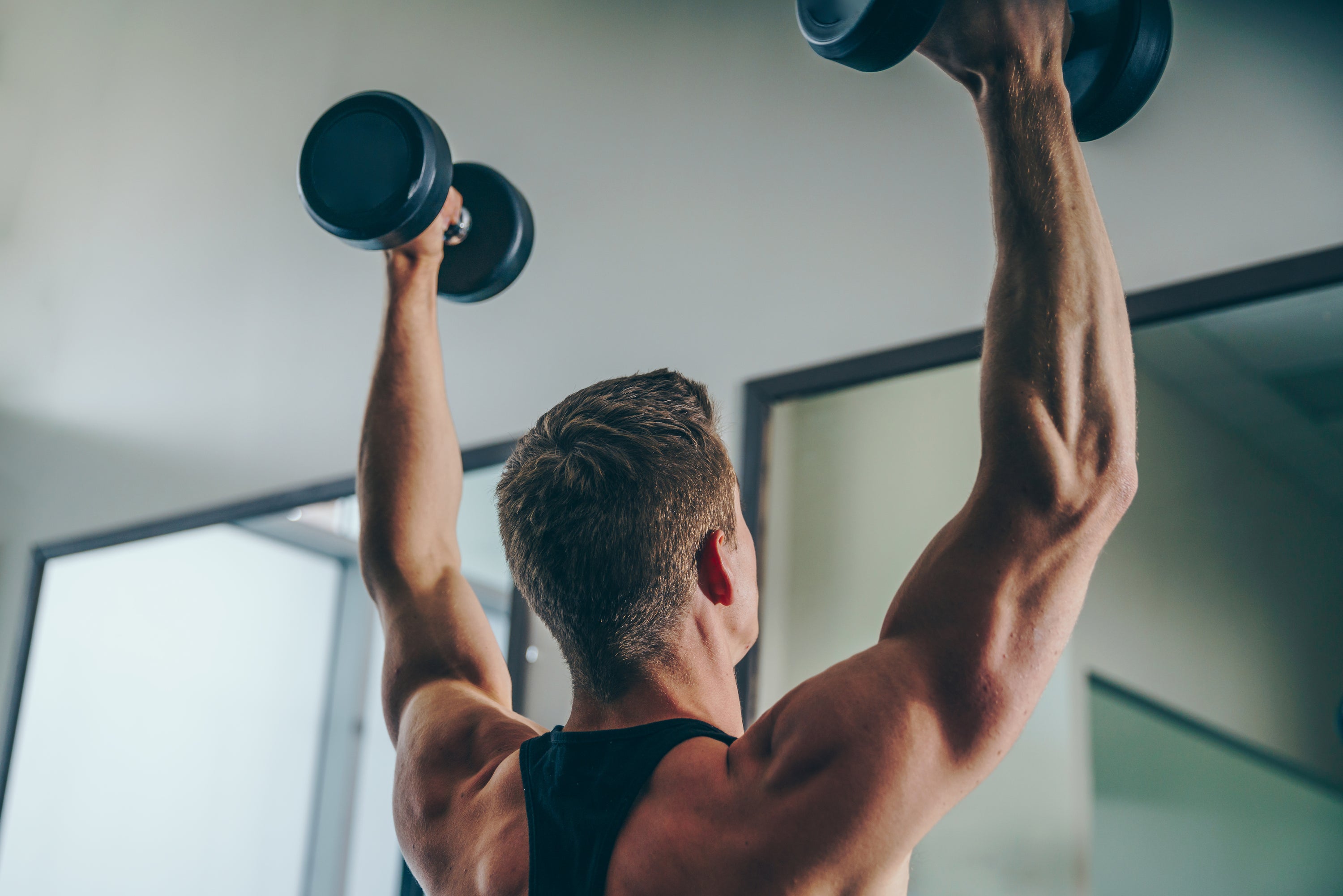 Man lifting dumbbells in home gym, strength training workout